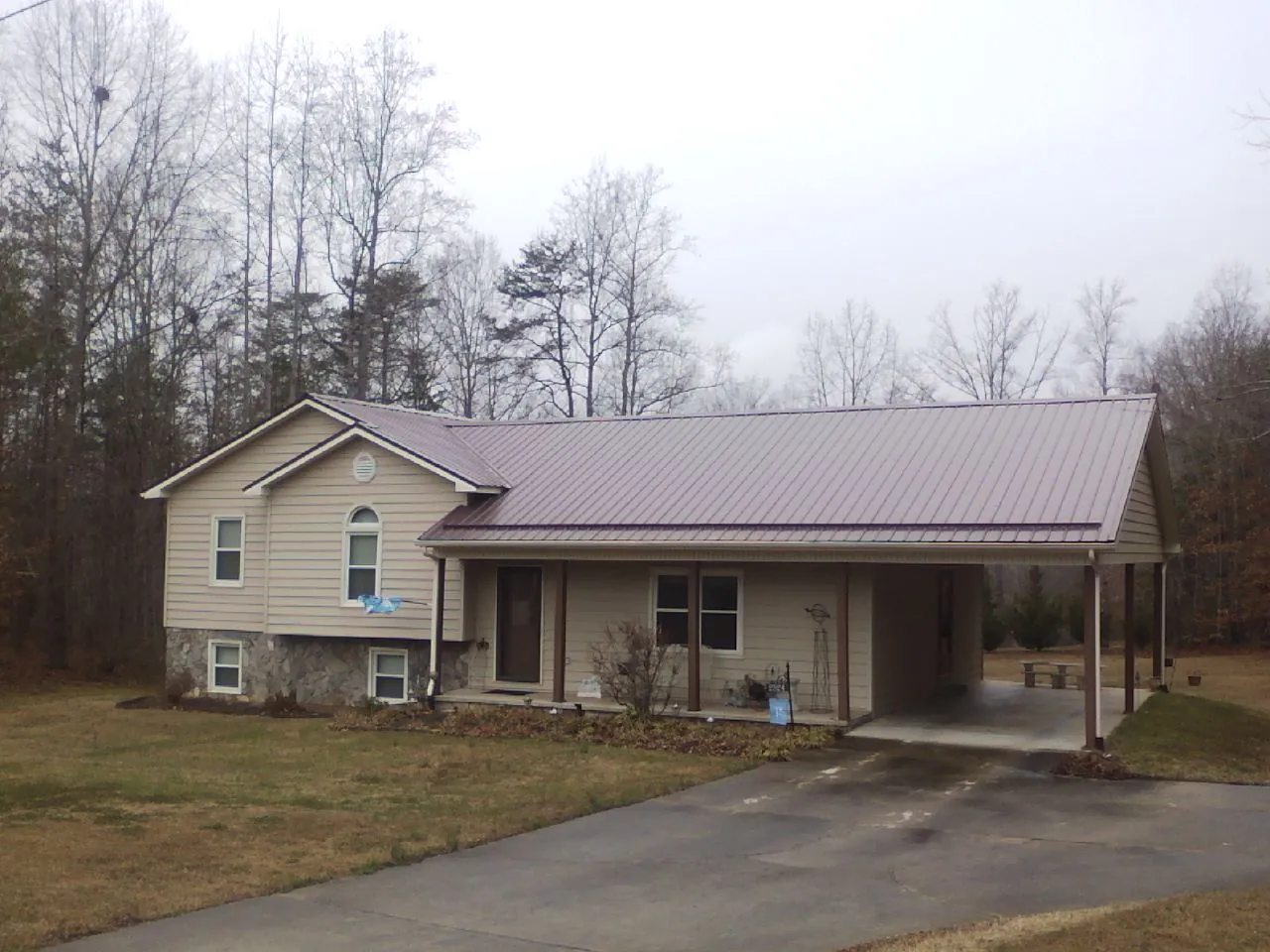 Burgundy metal roof on a tan split level home with an attached carport in Chappells