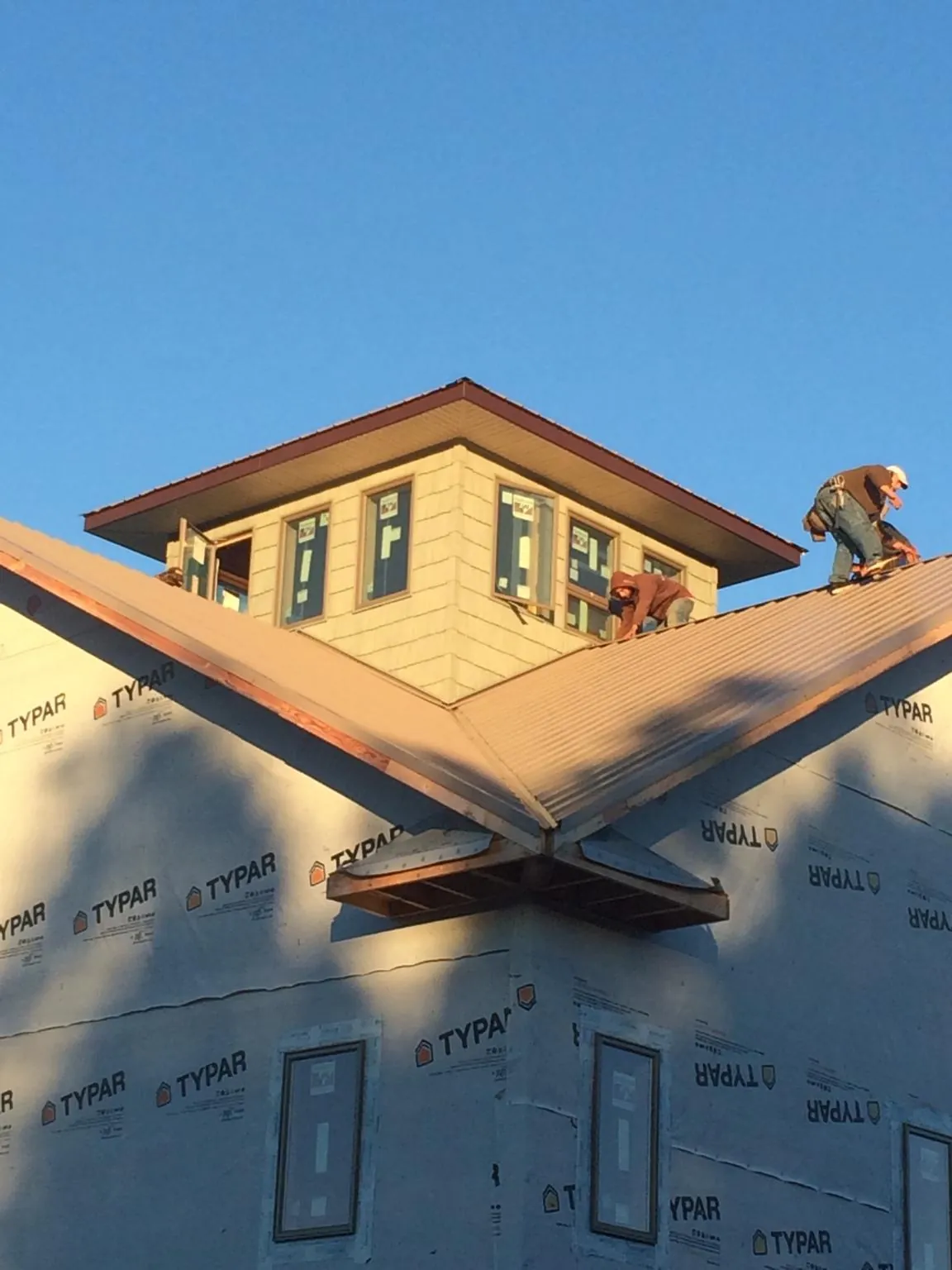 Roofers working around a rooftop cupola on a new metal roof at sunset — Roof Waterproofing in Chappells by Roofing Brothers